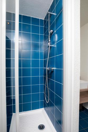 La salle de bains est pourvue de carrelage bleu et d'une douche. dans l'établissement SOWELL Family Pignada Plage, à Soustons