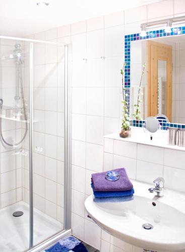 a white bathroom with a shower and a sink at Ferienwohnungen Gästehaus Schraudolf in Oberstdorf