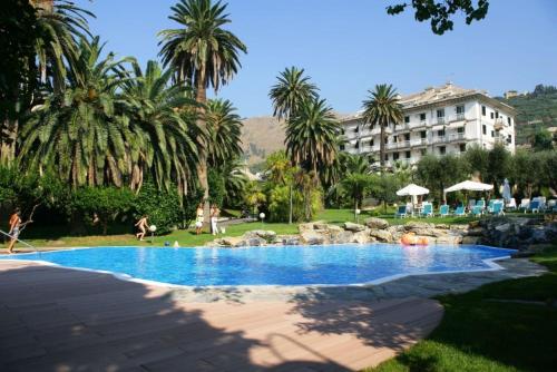 a swimming pool in a resort with palm trees and a building at Savoia Apartments in Genoa