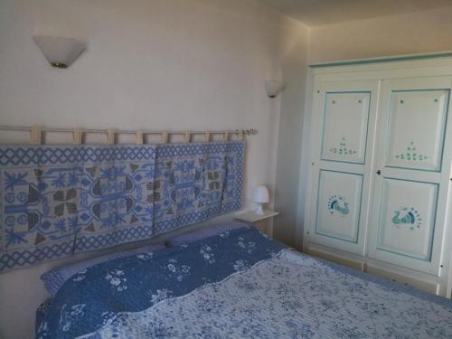 Schlafzimmer mit einem Bett mit einer blauen und weißen Bettdecke in der Unterkunft Domus Bellavista in Monte Nai