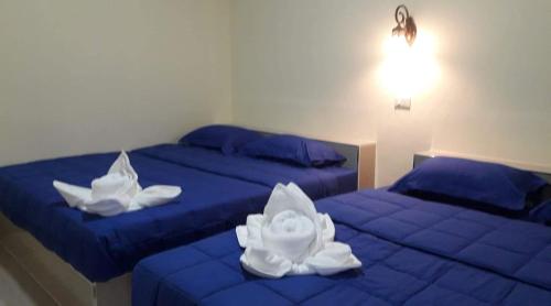 two beds with blue sheets and white towels on them at Lung Pod 9 resort in Chumphon