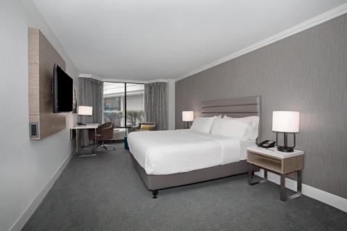 a bedroom with a bed and a desk and a television at Crowne Plaza Costa Mesa Orange County by IHG in Costa Mesa