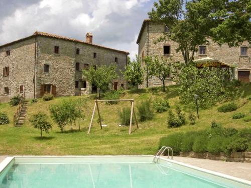 una piscina di fronte a un edificio in pietra e a una casa di Belvilla by OYO Casal Corniolo Montalto ad Apecchio