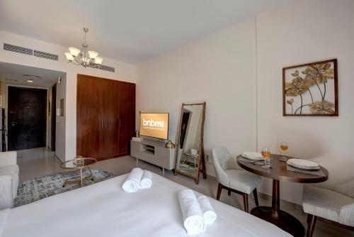 a hotel room with a bed and a table and a tv at bnbmehomes - Classic Studio Apt in the heart of JVC - 214 in Dubai
