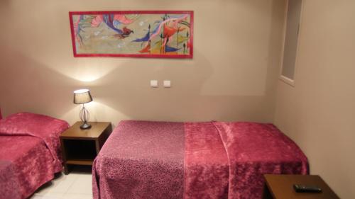 a room with two beds and a painting on the wall at Hôtel Savary in La Rochelle
