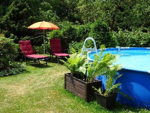 two chairs and an umbrella next to a swimming pool at Ferienwohnungen Weber in Friedrichsbrunn