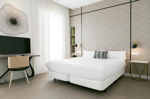 a white bedroom with a white bed and a tv at Teatro Romano 7 & 8 in Málaga