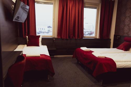 two beds in a hotel room with red curtains at Liljeholmens Stadshotell in Stockholm