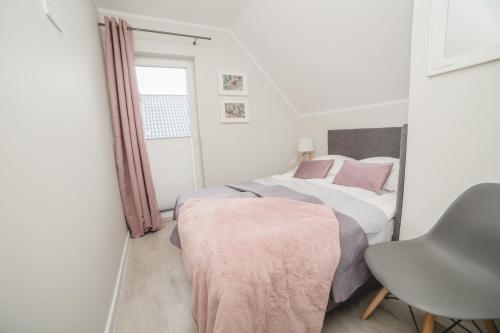 a bedroom with a bed and a chair and a window at Zagroda Liliowa in Dębki