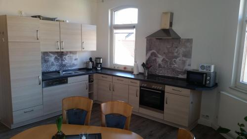 eine Küche mit weißen Schränken und einem Tisch und Stühlen in der Unterkunft Ferienwohnung "Burgblick" in Heldrungen