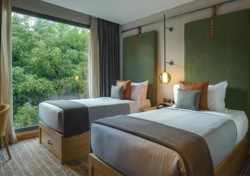a hotel room with two beds and a window at The Social House Nairobi, a Preferred Lifestyle Hotel in Nairobi