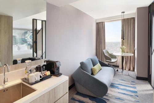 a hotel room with a chair and a mirror at Novotel Suites Yogyakarta Malioboro in Yogyakarta