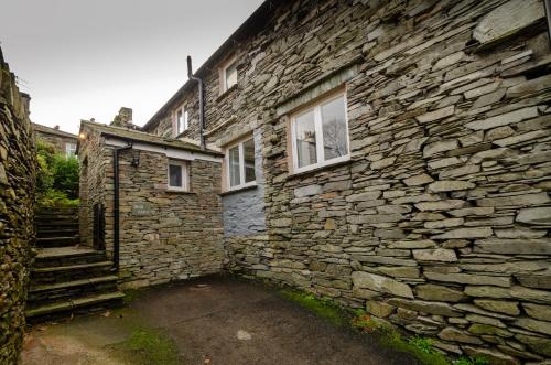 an old stone building with two windows and a staircase at High Barn, Ambleside in Ambleside