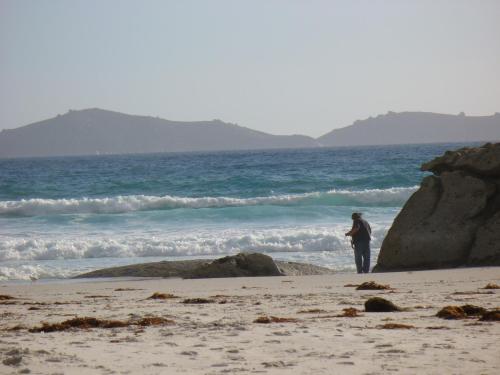 a person standing on a beach near the ocean at Prom Gate Getaway in Yanakie
