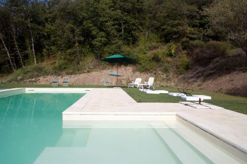 - Piscina con sombrilla, sillas y mesa en All'Antico Silbule en Capolona