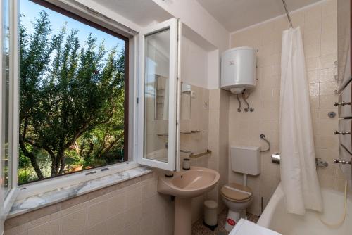 ein Bad mit einem Waschbecken, einem WC und einem Fenster in der Unterkunft Rooms Feme in Trogir