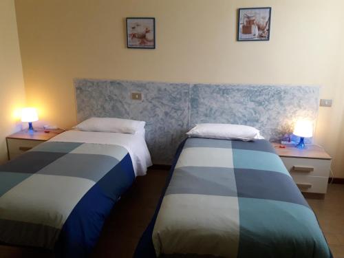 duas camas num quarto com duas lâmpadas nas mesas em La Casa Nel Verde 2 em Bolonha