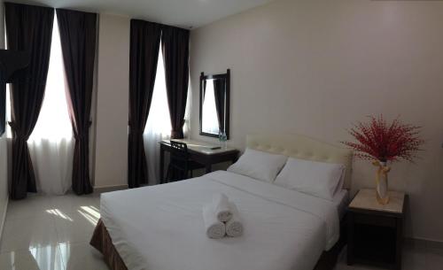 een slaapkamer met een wit bed en 2 handdoeken bij Sam Hotel in Sitiawan