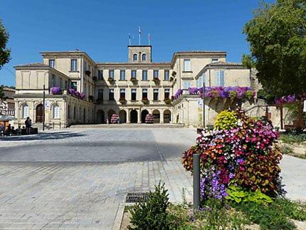 un grand bâtiment avec des fleurs devant lui dans l'établissement La maison des loirs, à Valréas