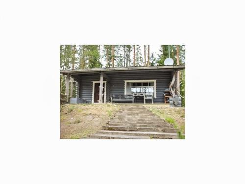 ein Haus im Wald mit einer Veranda und einer Treppe in der Unterkunft Holiday Home Heinälampi by Interhome in Laakkii