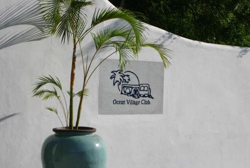 a plant in a green vase next to a sign at Ocean Village Club (Adults Only) in Diani Beach