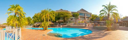 un complexe avec une piscine en face d'un bâtiment dans l'établissement Elephant Hills Resort, à Victoria Falls