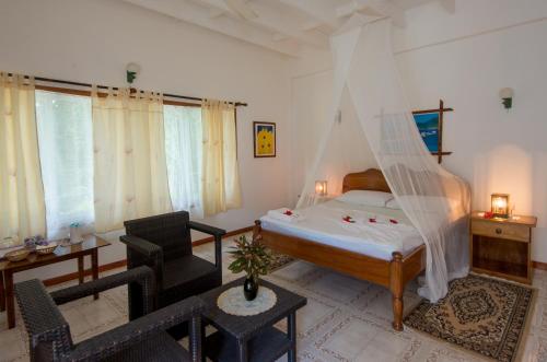 a bedroom with a bed with a mosquito net at Zerof Guest House in La Digue