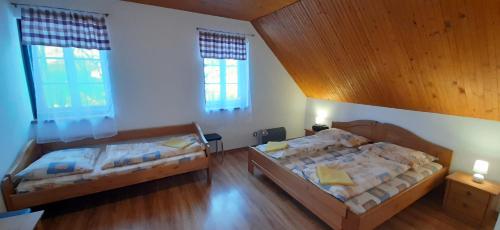 two beds in a room with two windows at Penzión Jánošíkova Krčma in Ružomberok