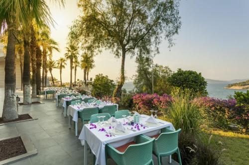 a row of tables and chairs with the ocean in the background at Duja Bodrum in Torba