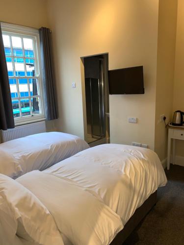 two beds in a room with a tv on the wall at Royal Oak Hotel in Leicester