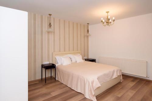 una camera con un letto e due tavoli e un lampadario a braccio di Tourist B&C a Curtea de Argeş