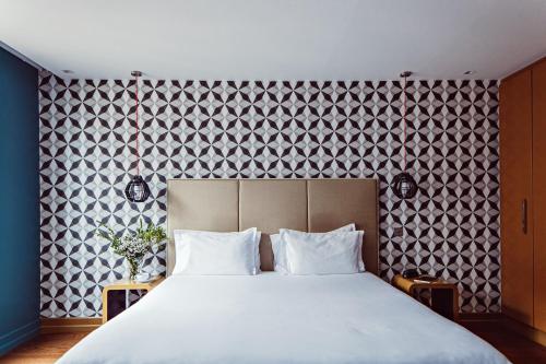 パリにあるムッシュ カデ ホテル ＆ スパの大きなベッドと模様のある壁が備わるベッドルーム1室が備わります。