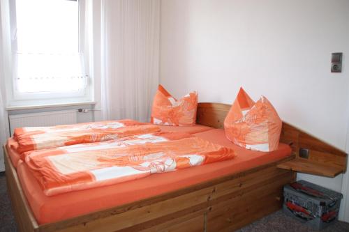uma cama com lençóis e almofadas cor de laranja em Ferienwohnung Michalla em Thale