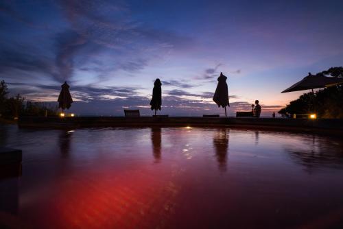 a pool of water with umbrellas and the sunset at The Houben - Adult Only in Ko Lanta