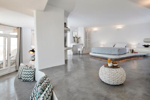 Dormitorio blanco con cama y mesa en Suites of the Gods Cave Spa Hotel, en Megalokori
