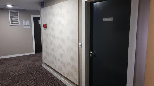 a black door in a hallway with a wall at Euro Hôtel Paris Créteil in Créteil