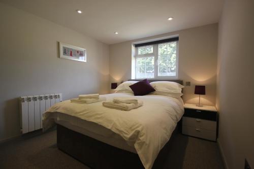 ein Schlafzimmer mit großem Bett und Fenster in der Unterkunft Flintstone Cottages in Chichester