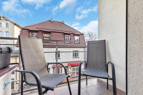 two chairs on a balcony with a building at Apartament Na Deptaku z Parkingiem i Klimatyzacją by Renters in Międzyzdroje