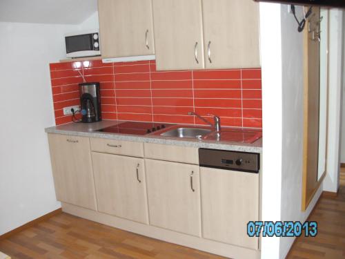 une cuisine avec un évier et un mur en carrelage rouge dans l'établissement Haus Znopp, à Saalbach-Hinterglemm