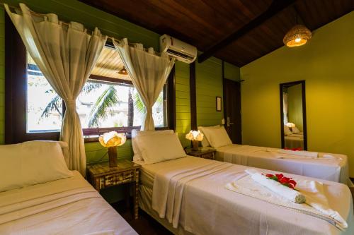 a bedroom with two beds with a window and a mirror at Pousada Naiepe in Fernando de Noronha