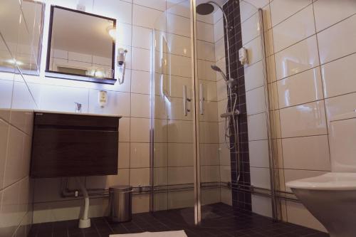 a shower in a bathroom with a sink and a mirror at Liljeholmens Stadshotell in Stockholm