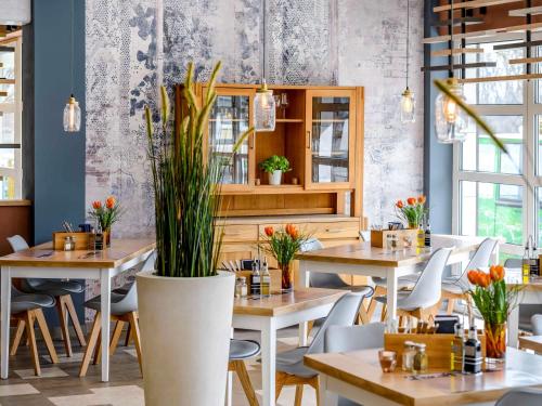 a restaurant with wooden tables and chairs and plants at Ibis Styles Regensburg in Regensburg