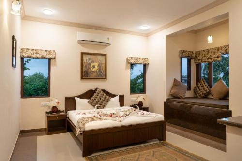 1 dormitorio con cama, sofá y ventanas en Araliayas Resort & Spa, en Udaipur