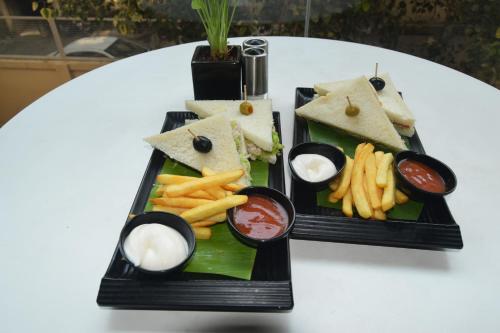 two black plates of food with sandwiches and french fries at Ginger Madgaon, Goa in Madgaon