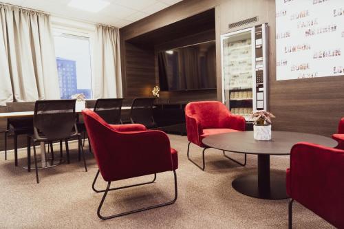 a waiting room with red chairs and a table at Liljeholmens Stadshotell in Stockholm