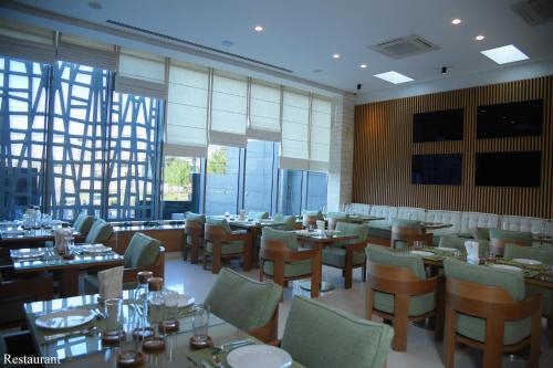 una sala da pranzo con tavoli, sedie e finestre di Hayali Boutique Hotel a Erbil