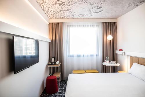 a hotel room with a bed and a tv at Hotel Ibis Krakow Centrum in Kraków