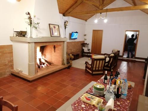 a living room with a fireplace and a table with wine bottles at Alojamento JCP in Bombarral