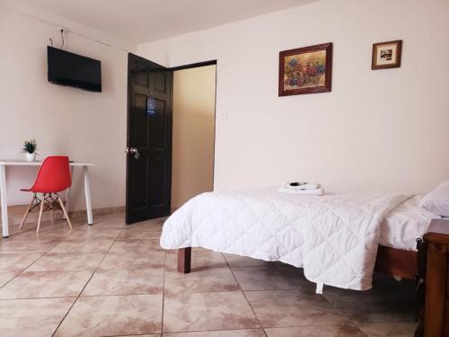 a bedroom with a bed and a table and a red chair at HOTEL TERRAZAS BOUTIQUE in Los Yoses