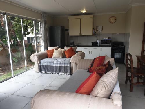 a living room with two couches and a kitchen at Amakaya Backpackers Travellers Accommodation in Plettenberg Bay